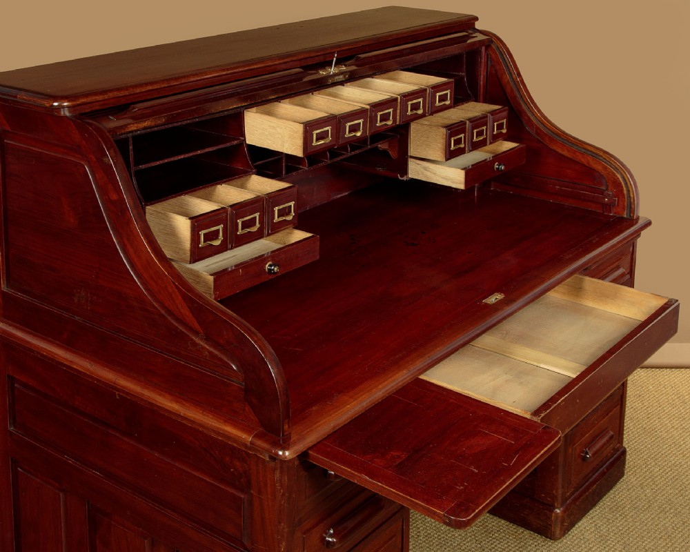 An Edwardian dark walnut roll top desk with a open slatted tambour shutter revealing interior drawers and pigeonholes above twin pedestal bases. View VIII