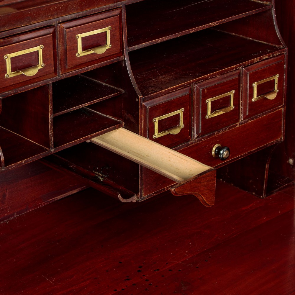 An Edwardian dark walnut roll top desk with a open slatted tambour shutter revealing interior drawers and pigeonholes above twin pedestal bases. View IX