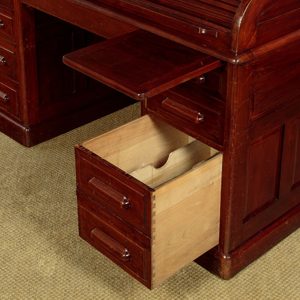 An Edwardian dark walnut roll top desk with a open slatted tambour shutter revealing interior drawers and pigeonholes above twin pedestal bases. View XII