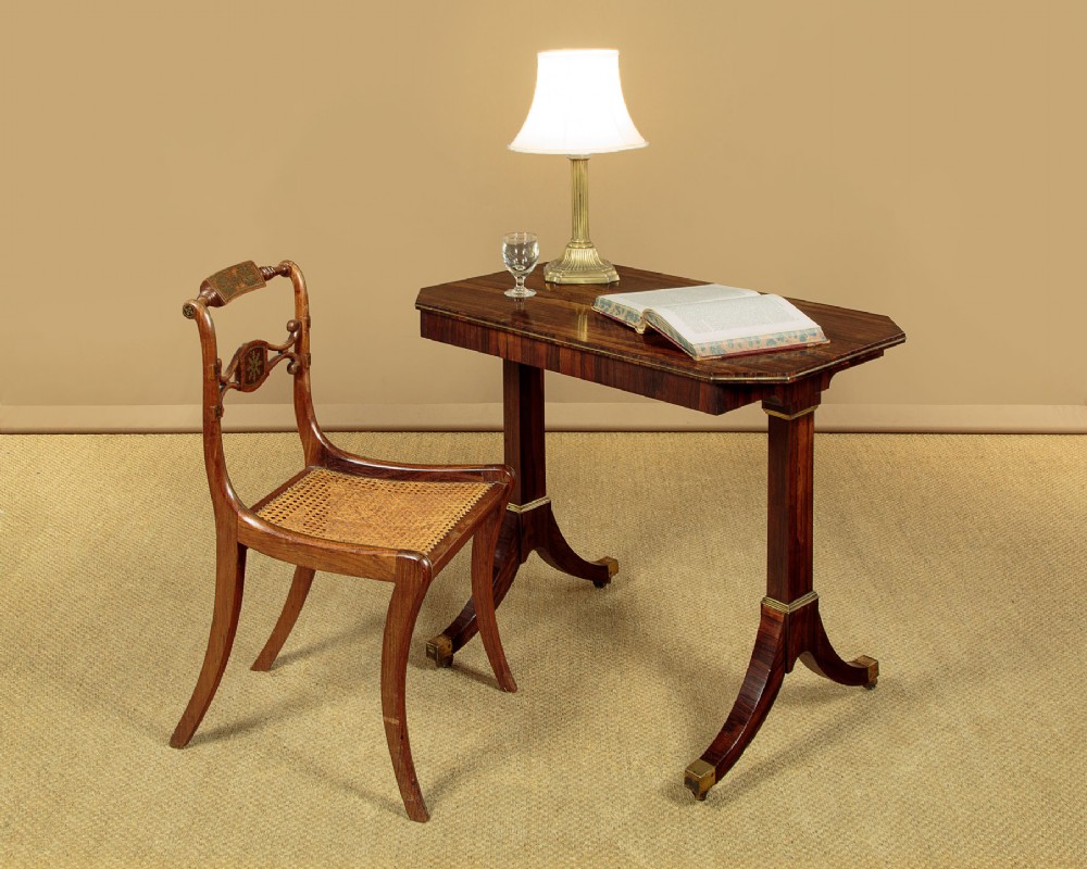 A Regency period rosewood writing table featuring a rectangular top with canted corners, brass beaded trim, twin end supports, and splayed legs with brass castors. View II