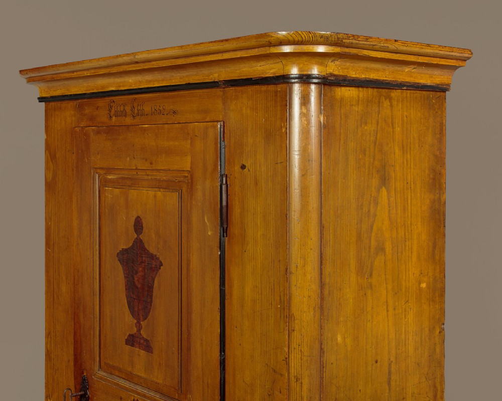 A single-door pine wardrobe featuring hand-painted urn motifs on two panelled sections and a dated inscription near the moulded cornice. View IV