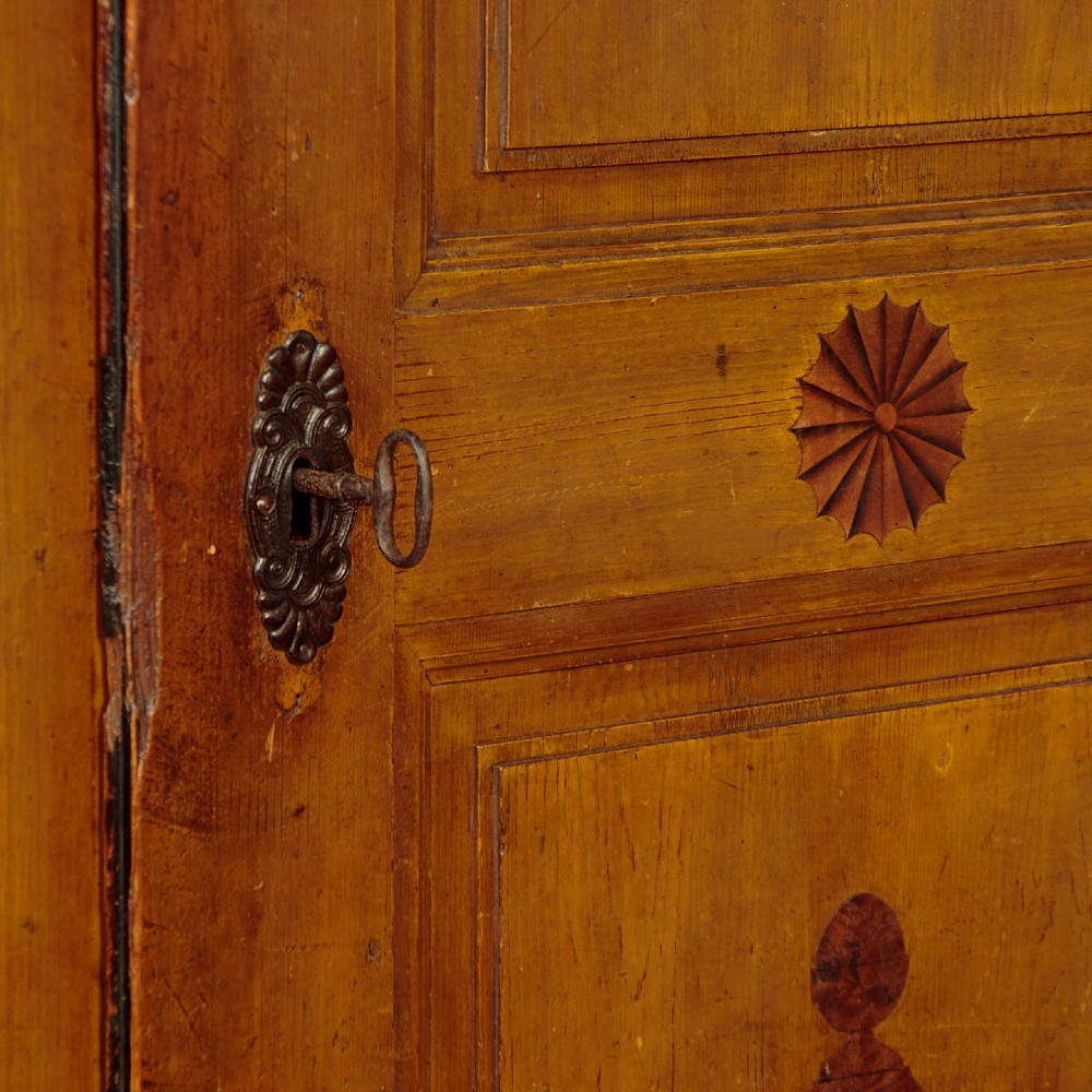 A single-door pine wardrobe featuring hand-painted urn motifs on two panelled sections and a dated inscription near the moulded cornice. View VII