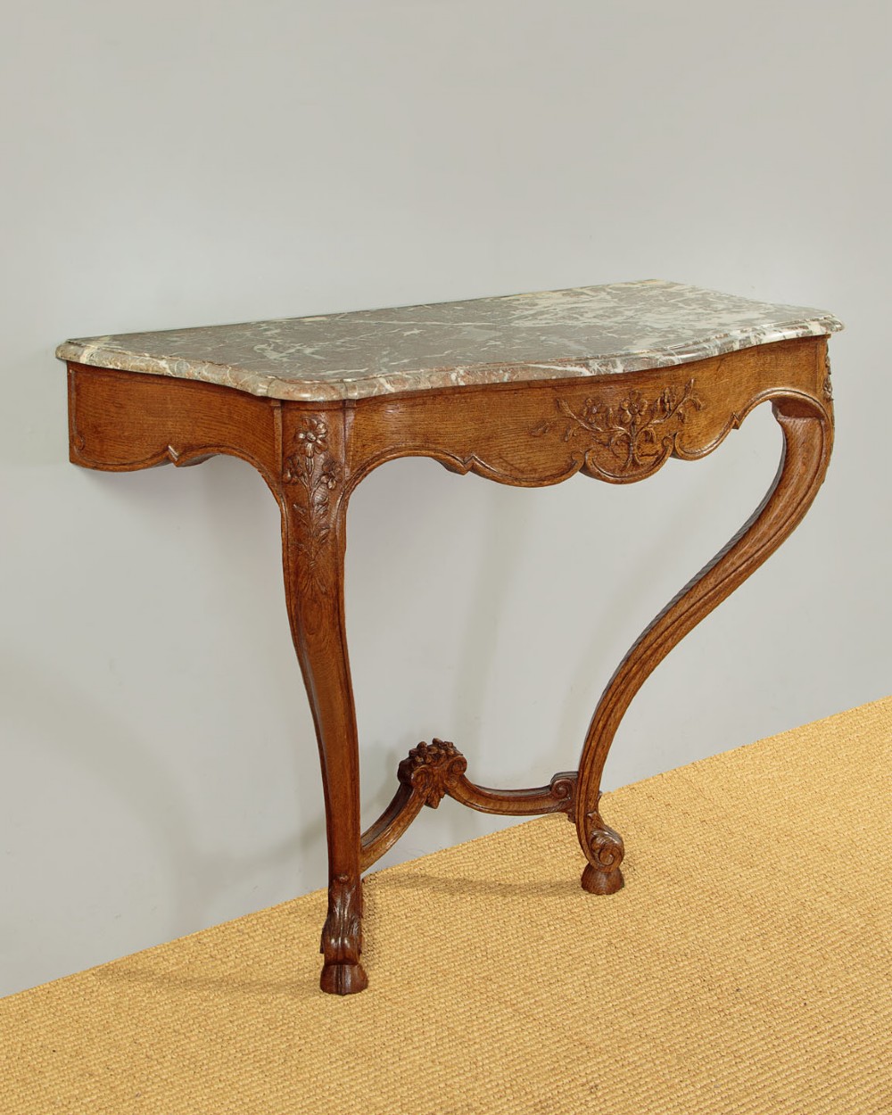 An oak console table featuring a shaped grey marble top, floral relief carvings along the apron, exaggerated cabriole legs, and a scrolled stretcher. View III