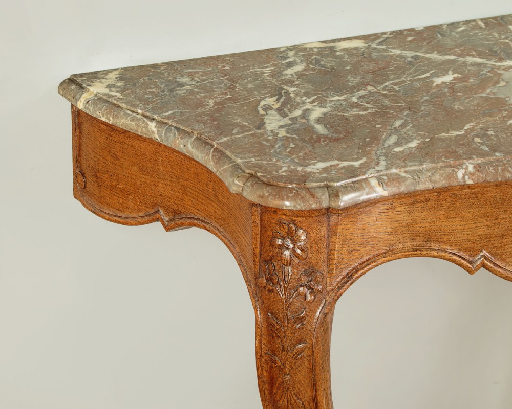 An oak console table featuring a shaped grey marble top, floral relief carvings along the apron, exaggerated cabriole legs, and a scrolled stretcher. View V