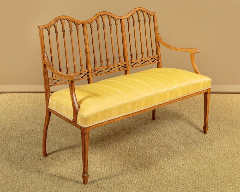 An antique inlaid satinwood triple chair-back settee featuring vertical splats, sweeping arms, and a yellow striped upholstered seat. View II