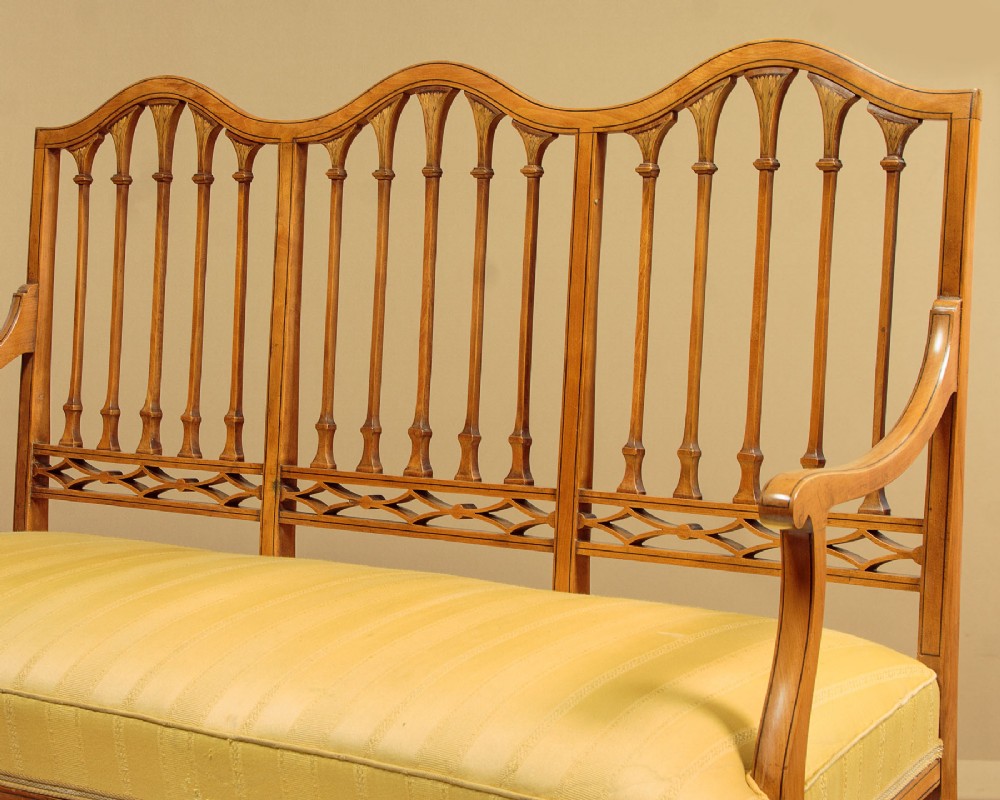 An antique inlaid satinwood triple chair-back settee featuring vertical splats, sweeping arms, and a yellow striped upholstered seat. View IV