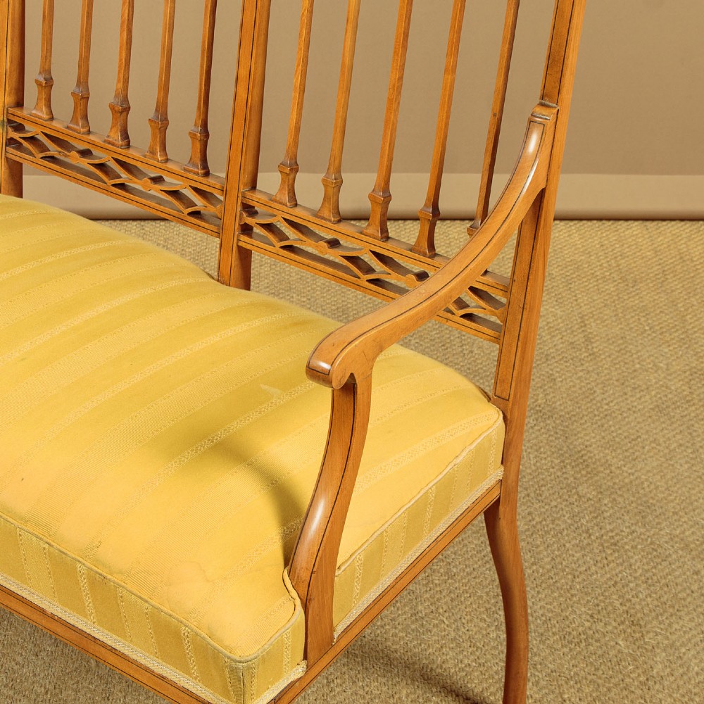 An antique inlaid satinwood triple chair-back settee featuring vertical splats, sweeping arms, and a yellow striped upholstered seat. View VII