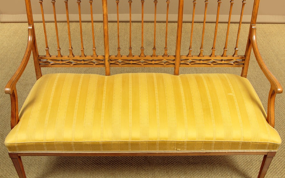 An antique inlaid satinwood triple chair-back settee featuring vertical splats, sweeping arms, and a yellow striped upholstered seat. View VIII