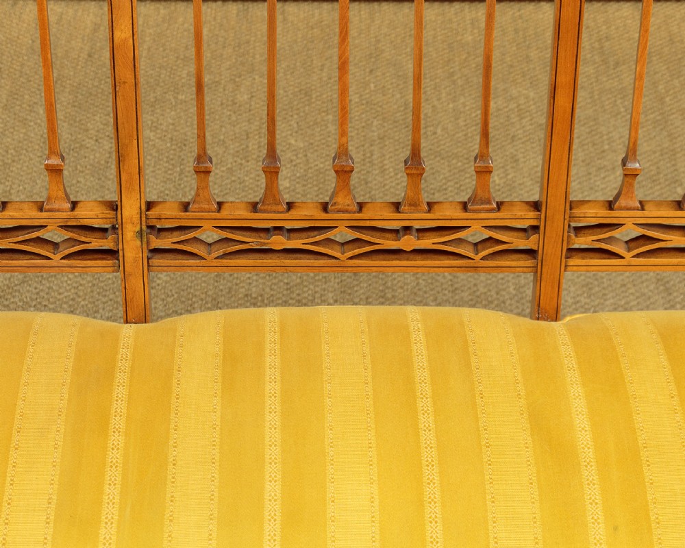 An antique inlaid satinwood triple chair-back settee featuring vertical splats, sweeping arms, and a yellow striped upholstered seat. View IX