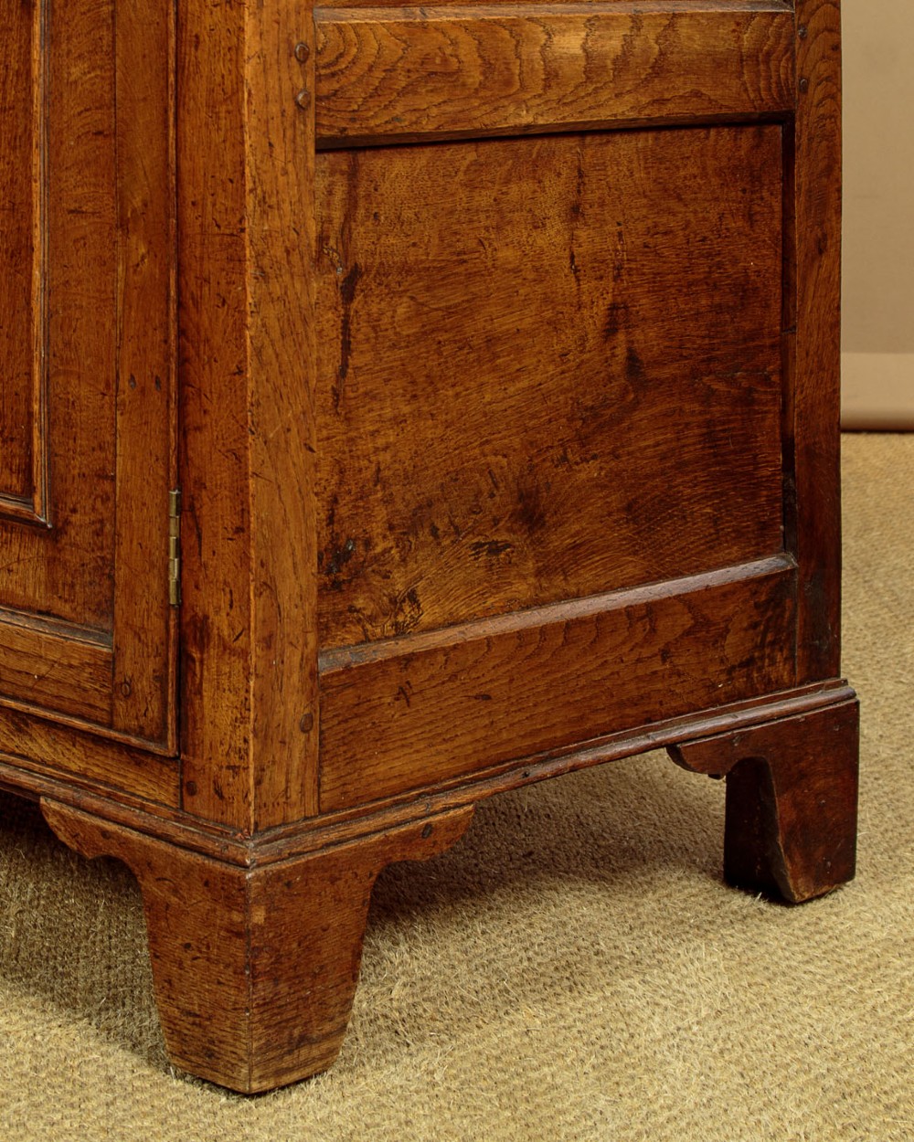 A late 18th-century warm brown oak Welsh dresser base featuring elevated top spice drawers, brass swan-neck handles, central drawers, and side cupboard doors. View XV