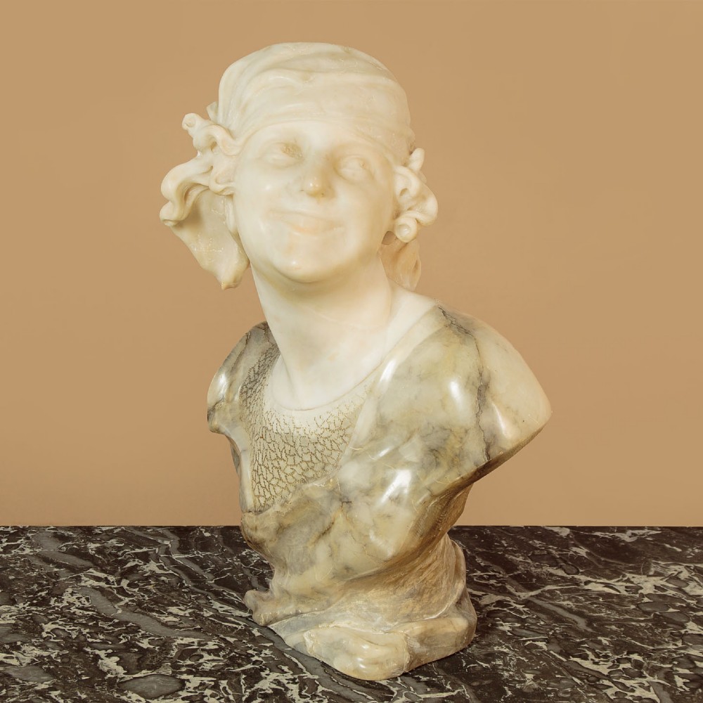 A carved antique alabaster bust of a woman wearing a headscarf tied with a bow, crafted from cream and veined stone. View III