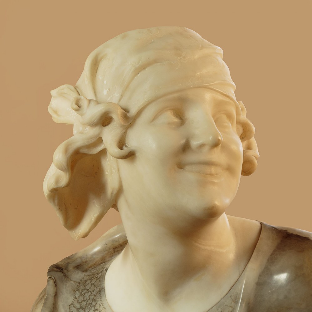 A carved antique alabaster bust of a woman wearing a headscarf tied with a bow, crafted from cream and veined stone. View IV