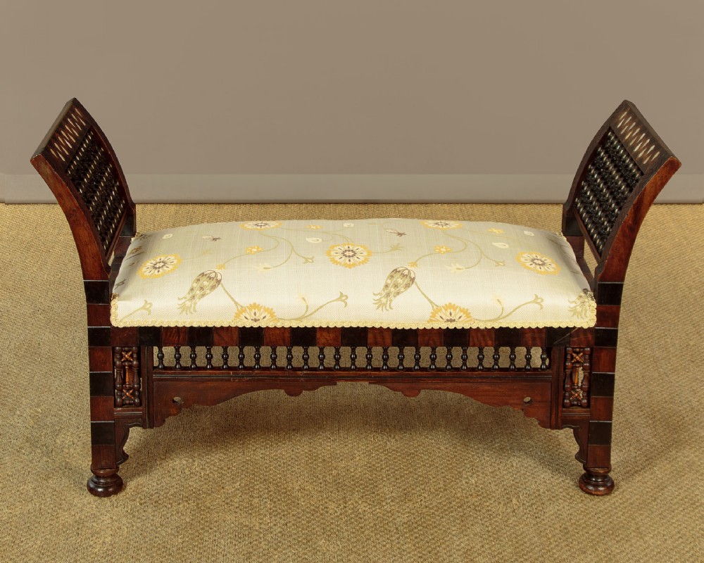 A Syrian dark wood window seat c.1920 with mother-of-pearl geometric inlay, turned lattice side panels, and a cream pattern-upholstered cushion. View II