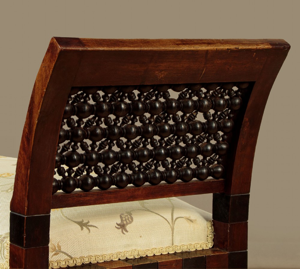 A Syrian dark wood window seat c.1920 with mother-of-pearl geometric inlay, turned lattice side panels, and a cream pattern-upholstered cushion. View VI