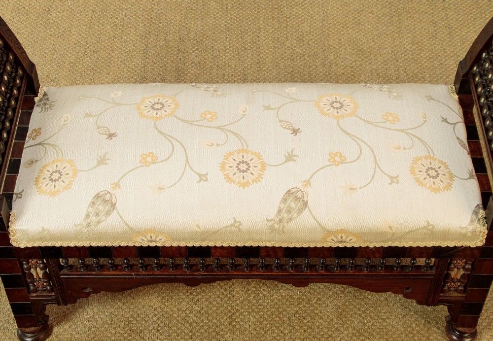 A Syrian dark wood window seat c.1920 with mother-of-pearl geometric inlay, turned lattice side panels, and a cream pattern-upholstered cushion. View VII