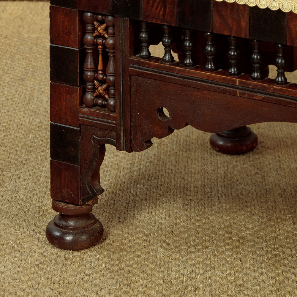 A Syrian dark wood window seat c.1920 with mother-of-pearl geometric inlay, turned lattice side panels, and a cream pattern-upholstered cushion. View XI
