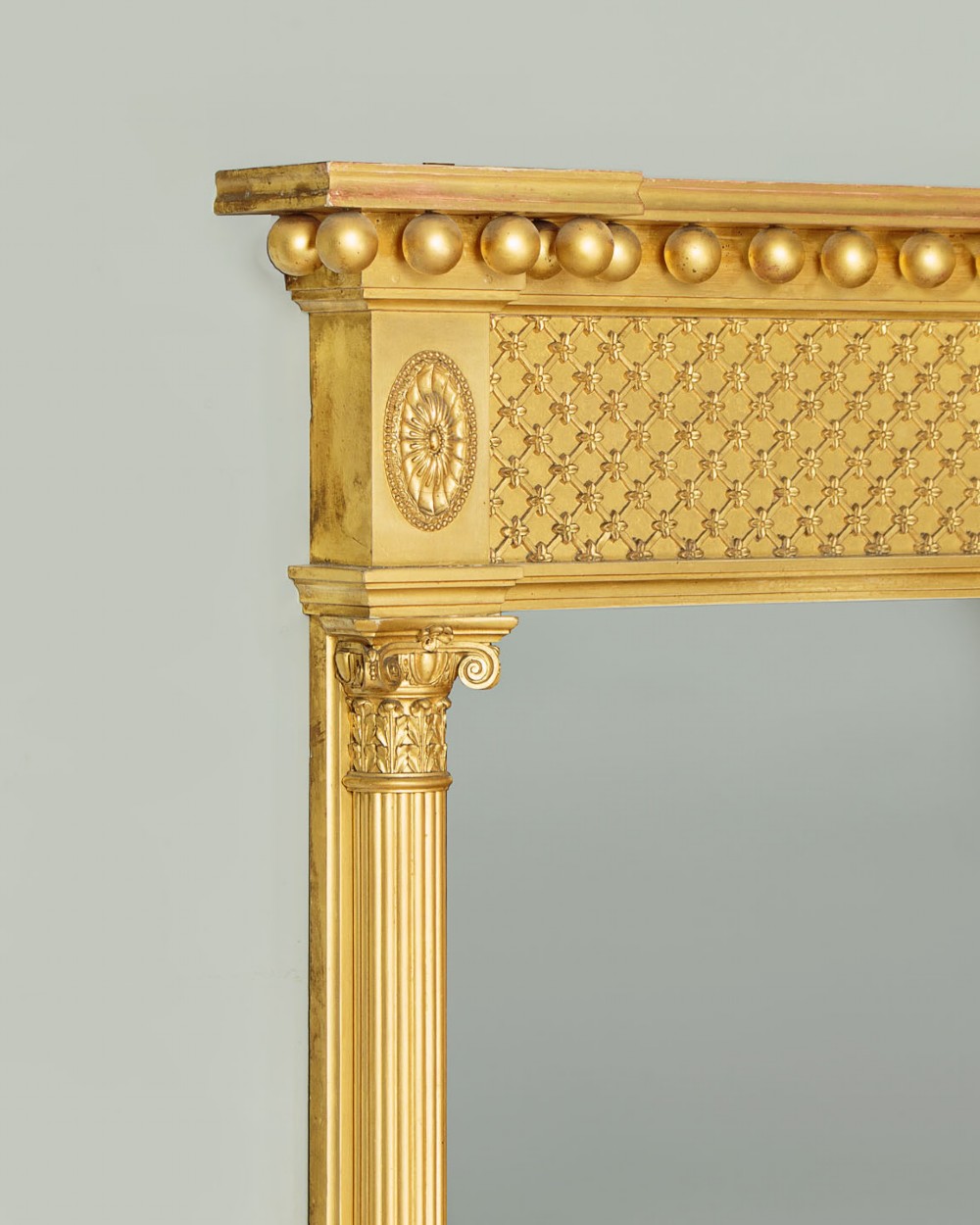 A large rectangular giltwood overmantel mirror featuring a decorated upper frieze with spherical mouldings and fluted side columns. View IV