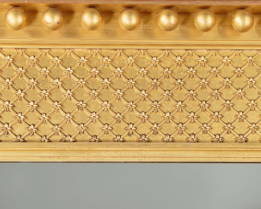 A large rectangular giltwood overmantel mirror featuring a decorated upper frieze with spherical mouldings and fluted side columns. View VI