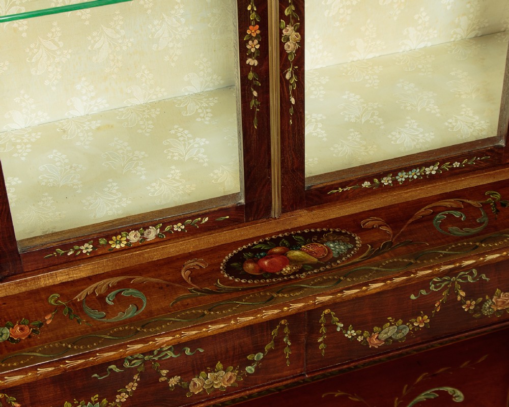 A dark mahogany display cabinet featuring hand-painted floral swags, classical urns, glass side panels, twin glazed doors, and tapered legs with an undertier. View VII