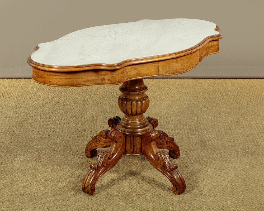 A nineteenth-century Victorian walnut centre table featuring a serpentine white marble top resting on a carved pedestal stem with scrolled tripod legs. View III
