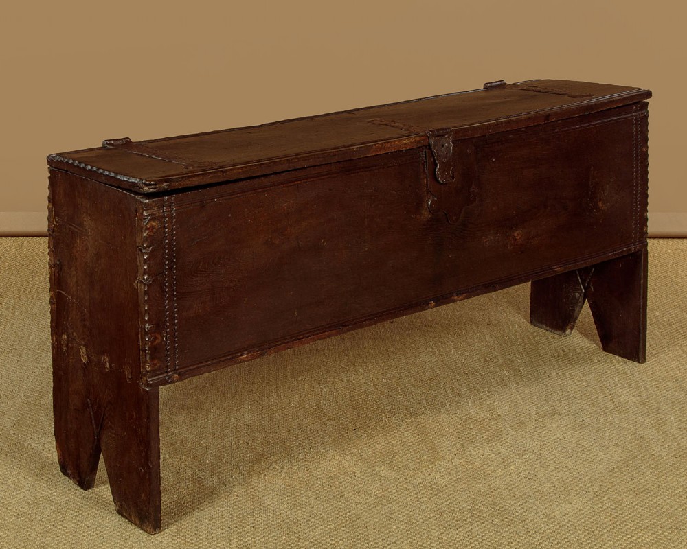 A long dark oak boarded sword chest featuring iron strap hinges and slab end supports. View III