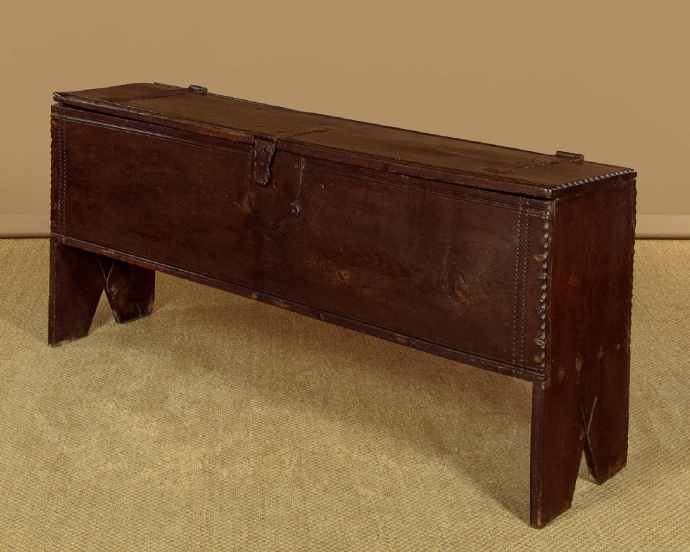 A long dark oak boarded sword chest featuring iron strap hinges and slab end supports. View IV