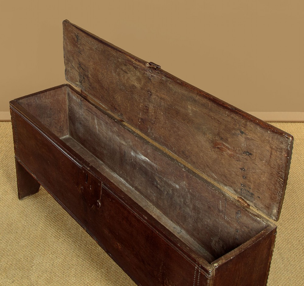A long dark oak boarded sword chest featuring iron strap hinges and slab end supports. View VI