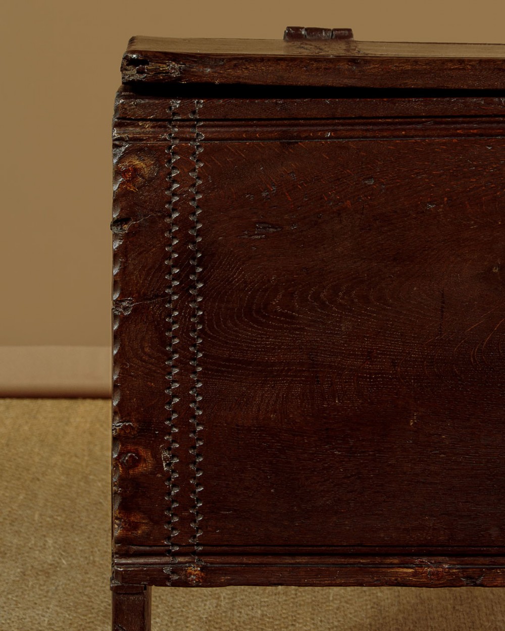 A long dark oak boarded sword chest featuring iron strap hinges and slab end supports. View IX