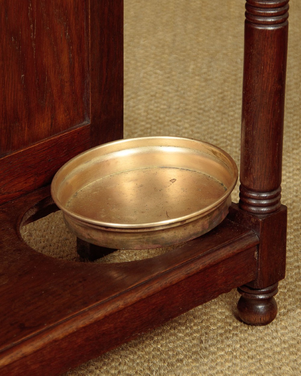 An Art Nouveau oak hallstand featuring an arched upper frame, brass coat hooks, central mirror, glove box, and bottom umbrella stand with two brass drip trays. View XI
