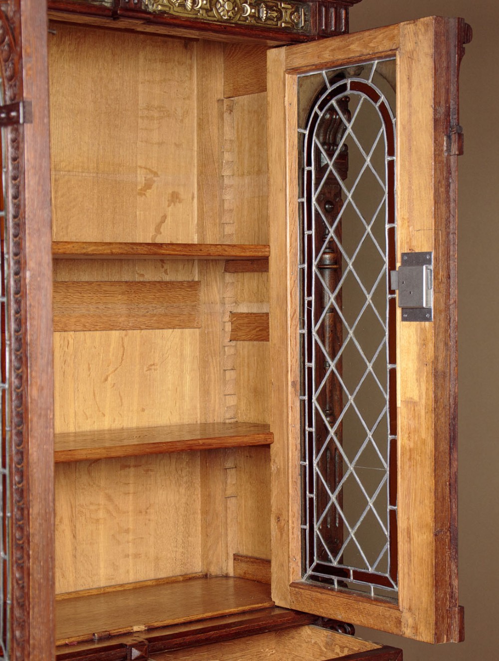 A carved dark oak Victorian secretaire bookcase featuring leaded glass upper doors, embossed brass panels, and gadrooned feet. View VI