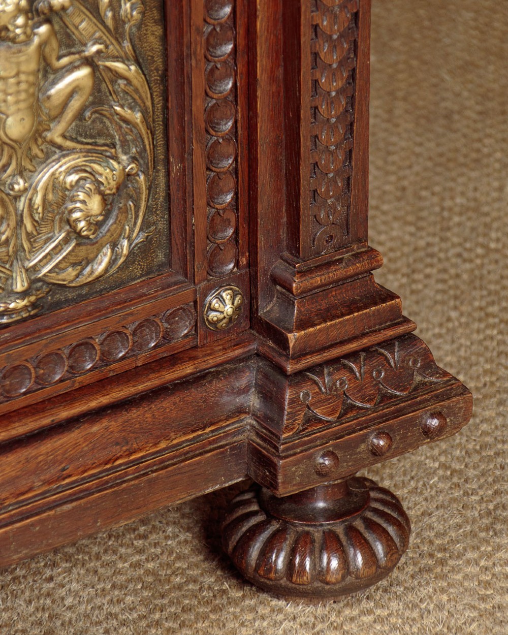 A carved dark oak Victorian secretaire bookcase featuring leaded glass upper doors, embossed brass panels, and gadrooned feet. View XIV