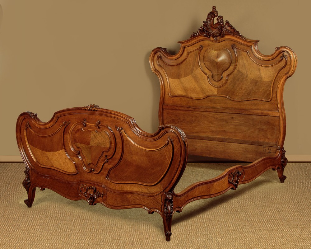 An antique French double bed frame crafted from carved walnut featuring serpentine edges, shell motifs, and book-matched veneered panels on the headboard and footboard. View II