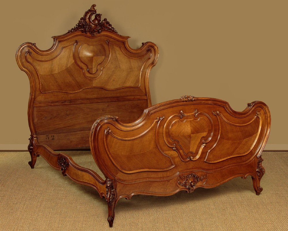 An antique French double bed frame crafted from carved walnut featuring serpentine edges, shell motifs, and book-matched veneered panels on the headboard and footboard. View III