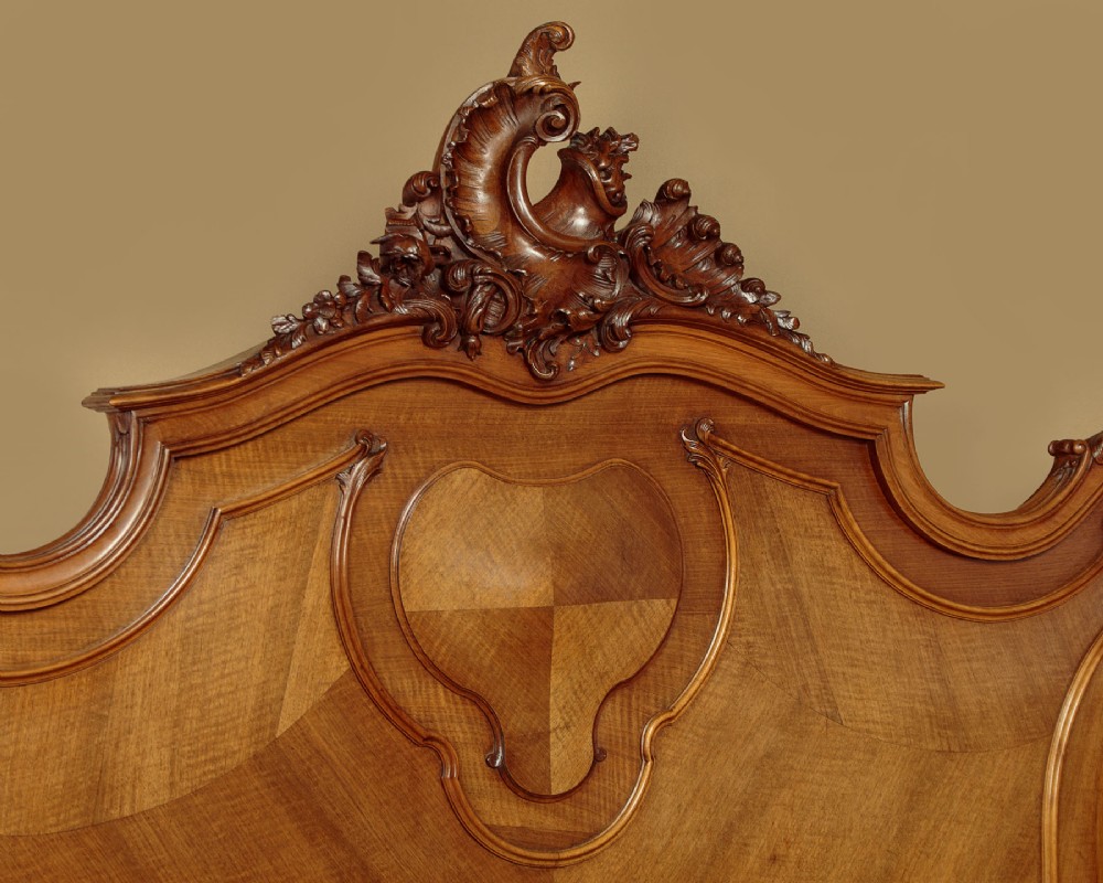 An antique French double bed frame crafted from carved walnut featuring serpentine edges, shell motifs, and book-matched veneered panels on the headboard and footboard. View IV