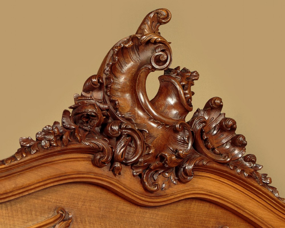 An antique French double bed frame crafted from carved walnut featuring serpentine edges, shell motifs, and book-matched veneered panels on the headboard and footboard. View V