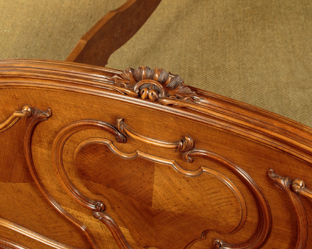An antique French double bed frame crafted from carved walnut featuring serpentine edges, shell motifs, and book-matched veneered panels on the headboard and footboard. View VIII