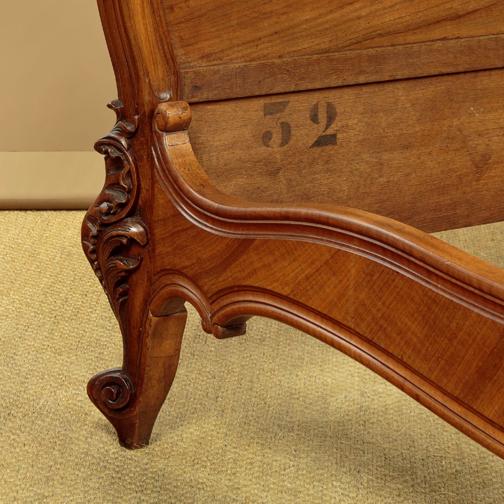 An antique French double bed frame crafted from carved walnut featuring serpentine edges, shell motifs, and book-matched veneered panels on the headboard and footboard. View X