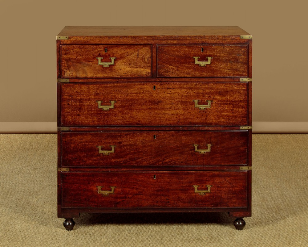 A Victorian mahogany military campaign chest featuring brass corner bindings, flush handles, two short drawers over three long drawers, resting on turned feet.