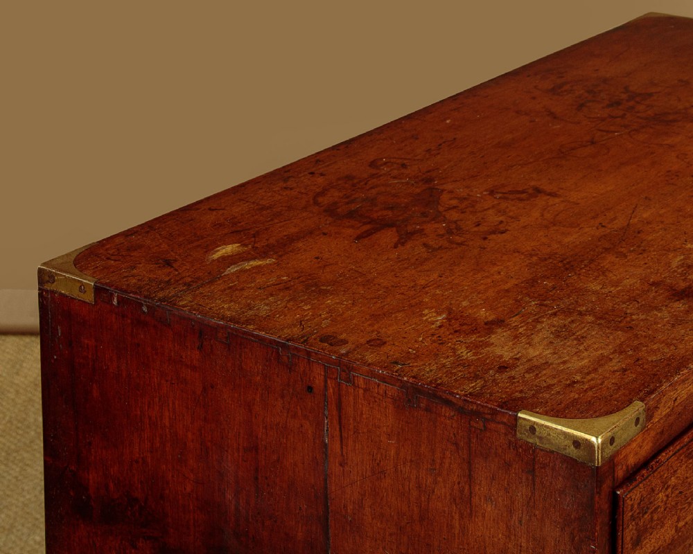 A Victorian mahogany military campaign chest featuring brass corner bindings, flush handles, two short drawers over three long drawers, resting on turned feet. View VII