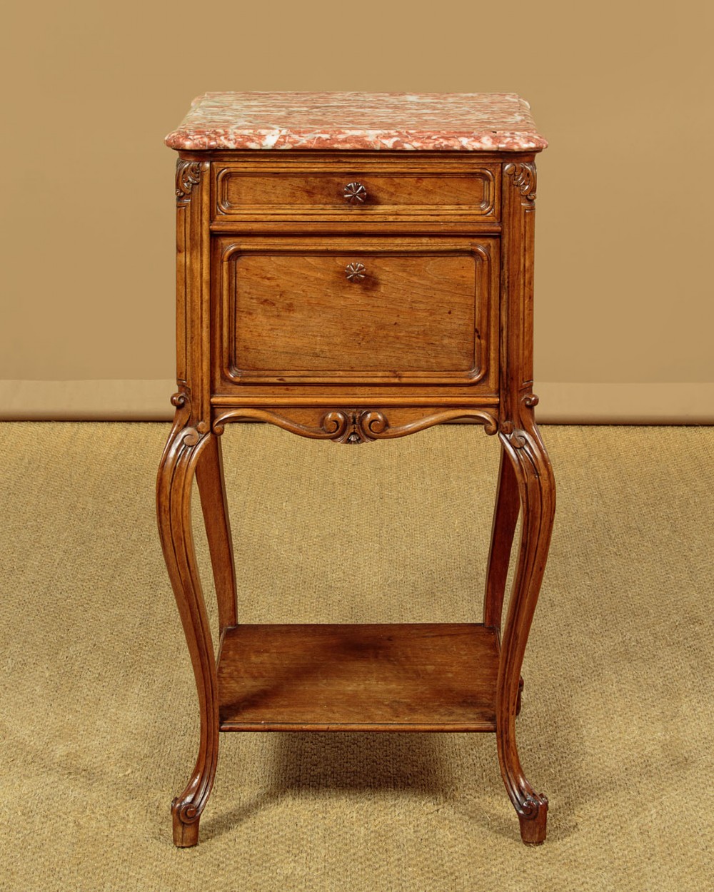 A pair of early twentieth-century walnut bedside cabinets featuring carved cabriole legs and pink variegated marble tops. View V