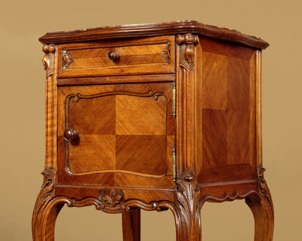 A pair of early twentieth-century walnut bedside cabinets featuring carved cabriole legs and pink variegated marble tops. View X