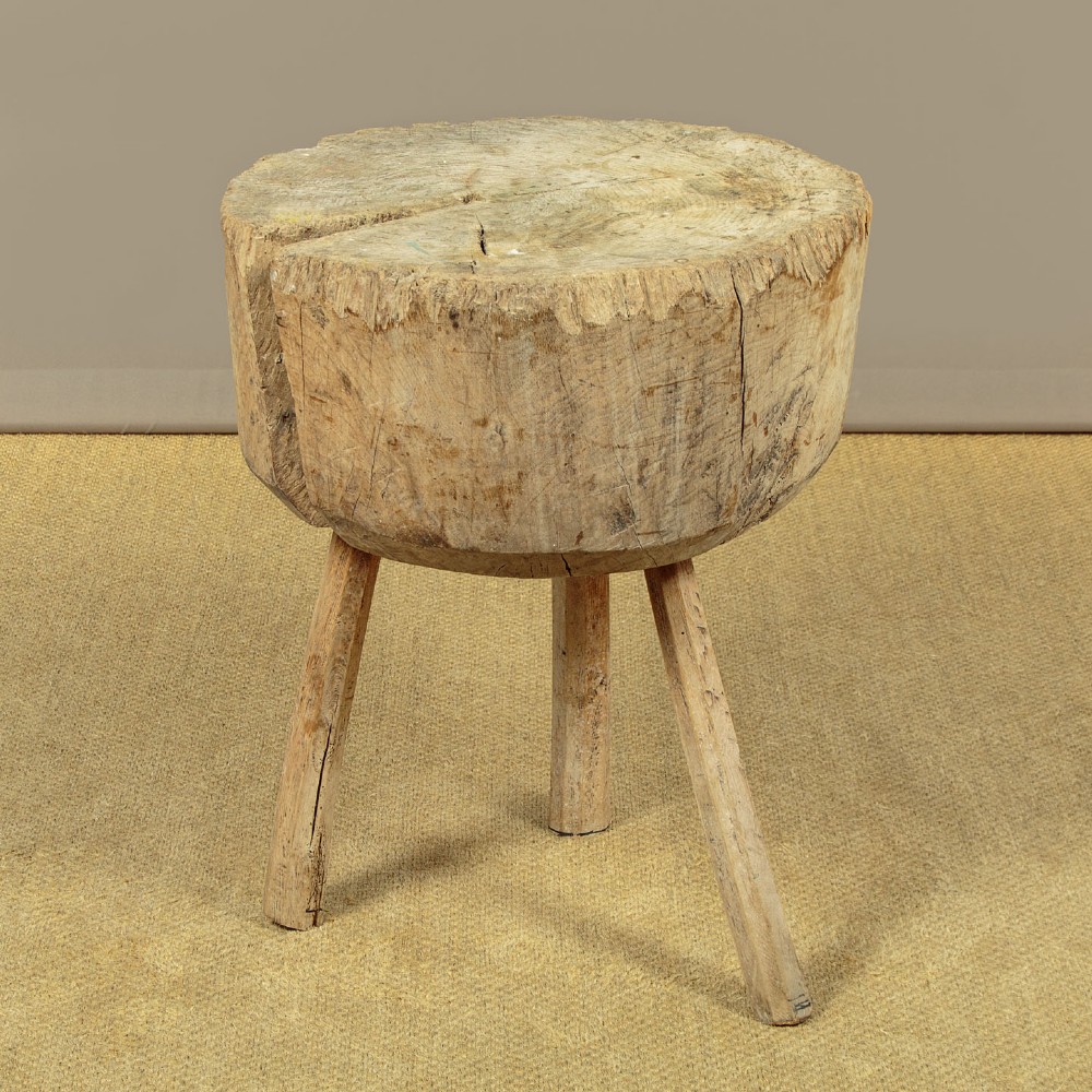 A rustic French provincial elm chopping block featuring a thick cylindrical wood top with three splayed timber legs.