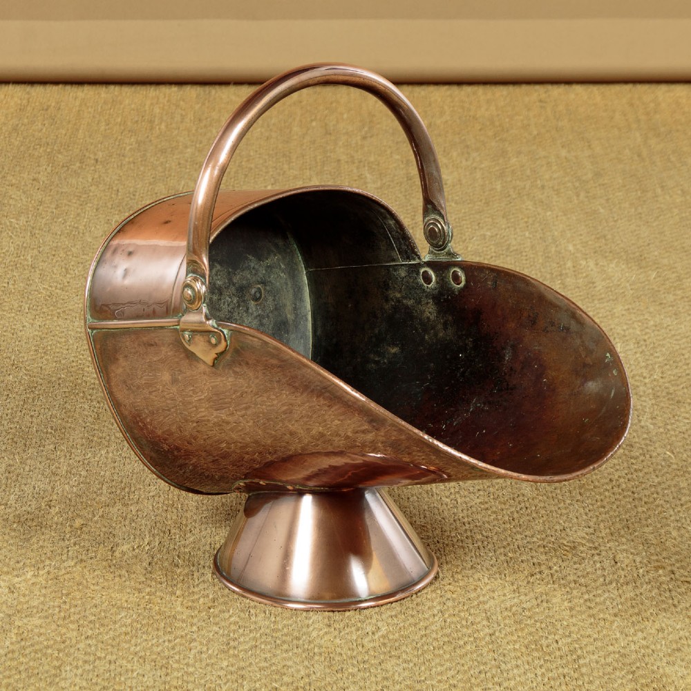 A pair of Victorian copper helmet-style coal scuttles featuring flared circular pedestals and curved swing handles. View IV