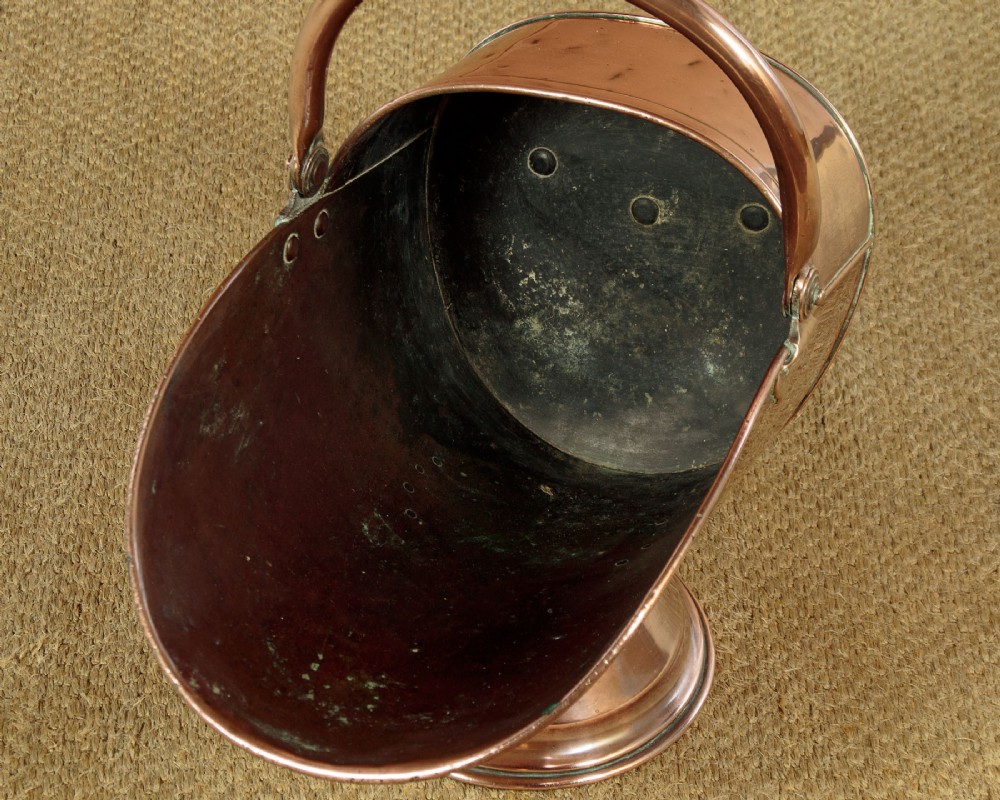 A pair of Victorian copper helmet-style coal scuttles featuring flared circular pedestals and curved swing handles. View VIII