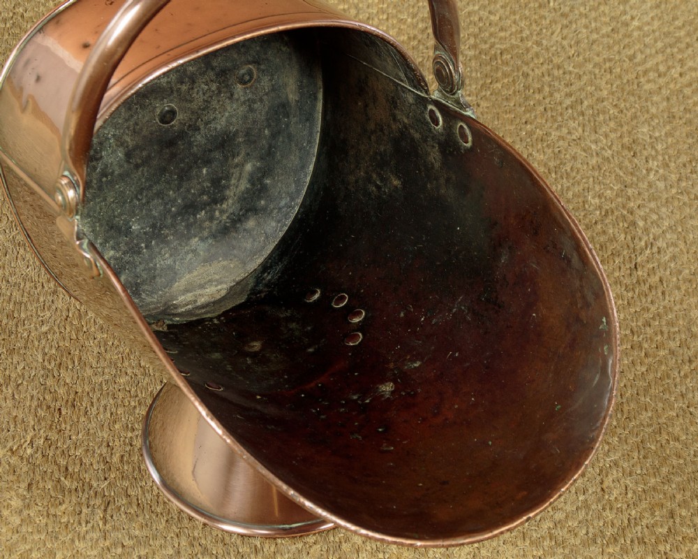 A pair of Victorian copper helmet-style coal scuttles featuring flared circular pedestals and curved swing handles. View IX