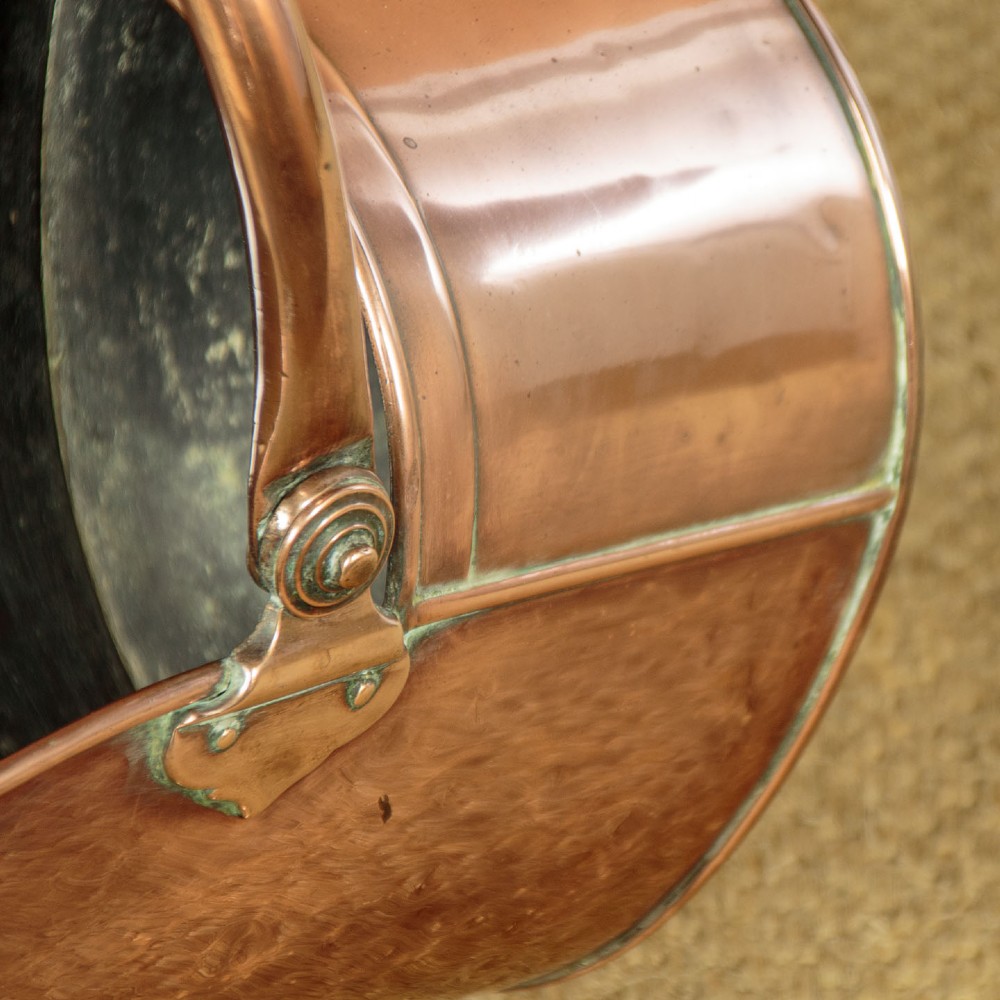 A pair of Victorian copper helmet-style coal scuttles featuring flared circular pedestals and curved swing handles. View XI