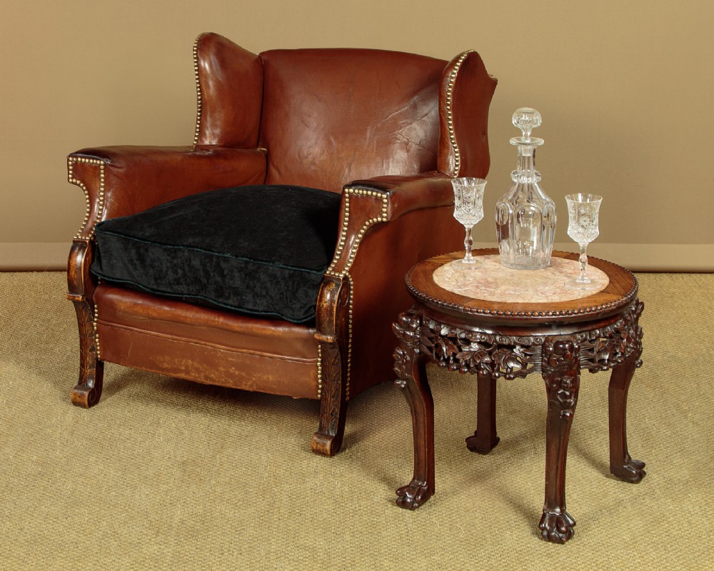 A low circular dark hardwood side table featuring an inset circular pink marble top, deeply carved floral aprons, and cabriole legs terminating in claw feet. View II
