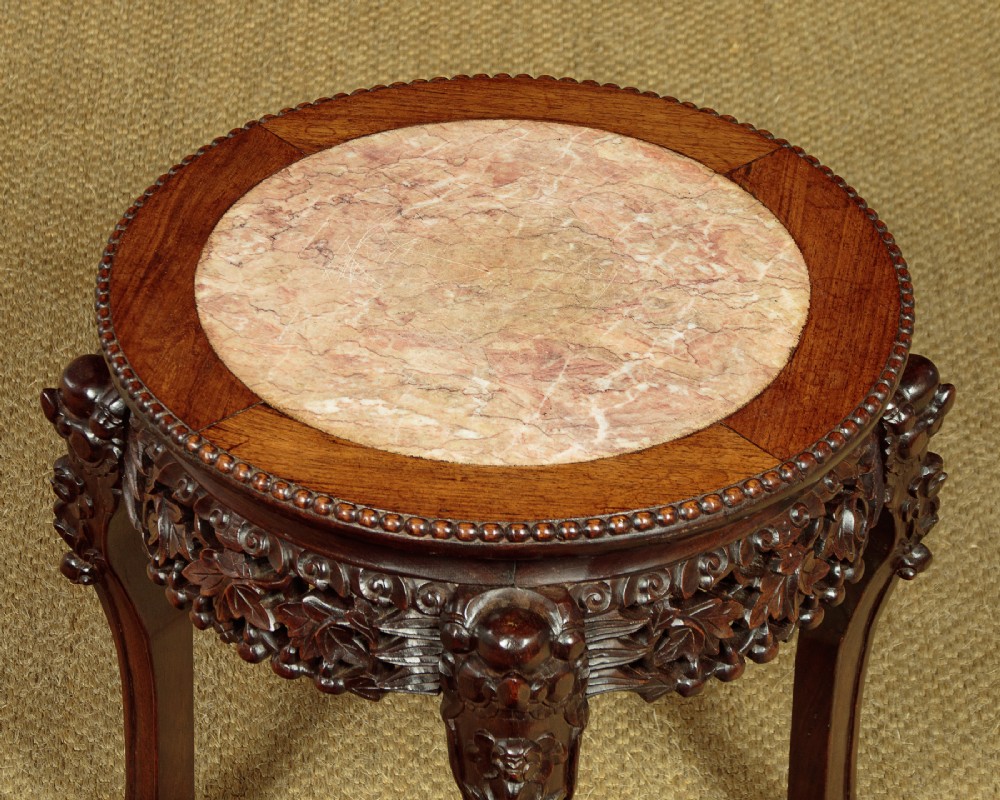 A low circular dark hardwood side table featuring an inset circular pink marble top, deeply carved floral aprons, and cabriole legs terminating in claw feet. View IV