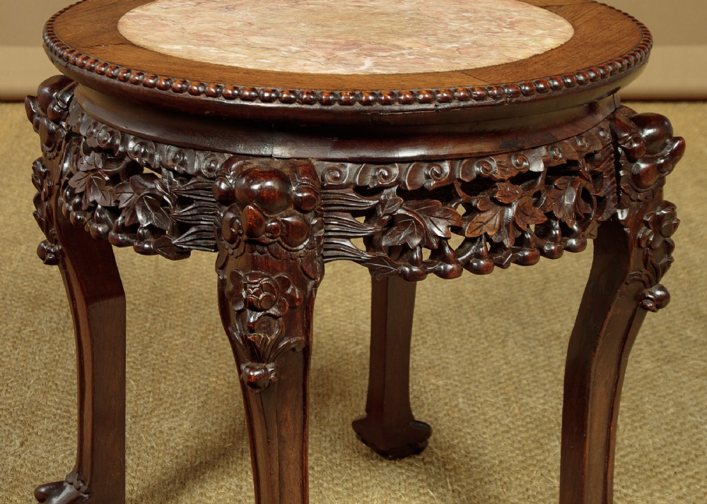 A low circular dark hardwood side table featuring an inset circular pink marble top, deeply carved floral aprons, and cabriole legs terminating in claw feet. View VI