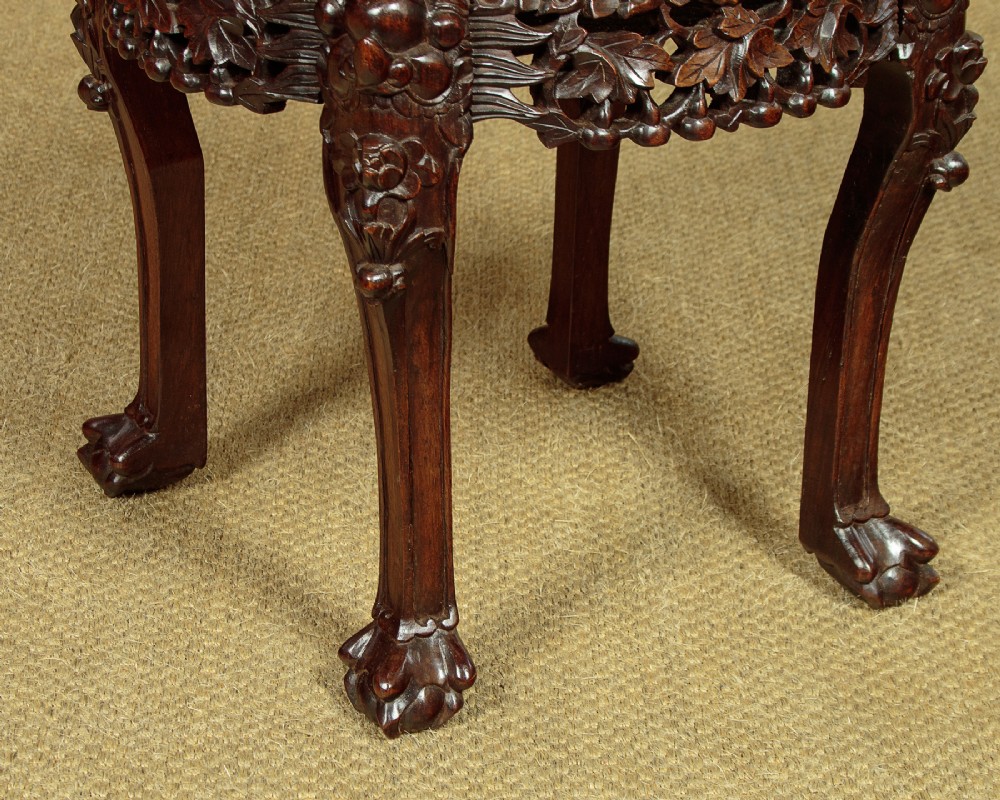 A low circular dark hardwood side table featuring an inset circular pink marble top, deeply carved floral aprons, and cabriole legs terminating in claw feet. View VII